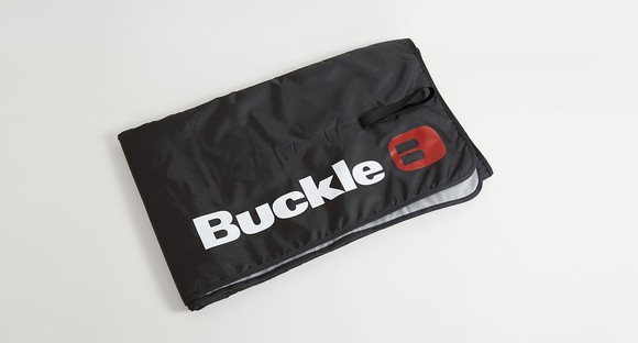 Folded black beach blanket with the Buckle logo on it.