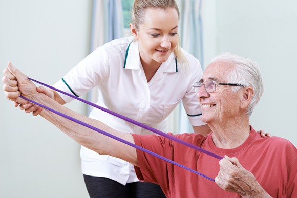 An older man works with a physical therapist.