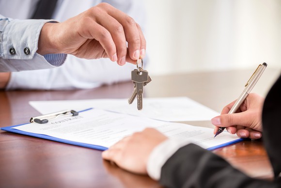 Handing keys to person signing paperwork.