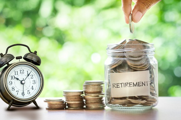A clock next to three stacks of coins and a jar filled with coins that has the word retirement on it.