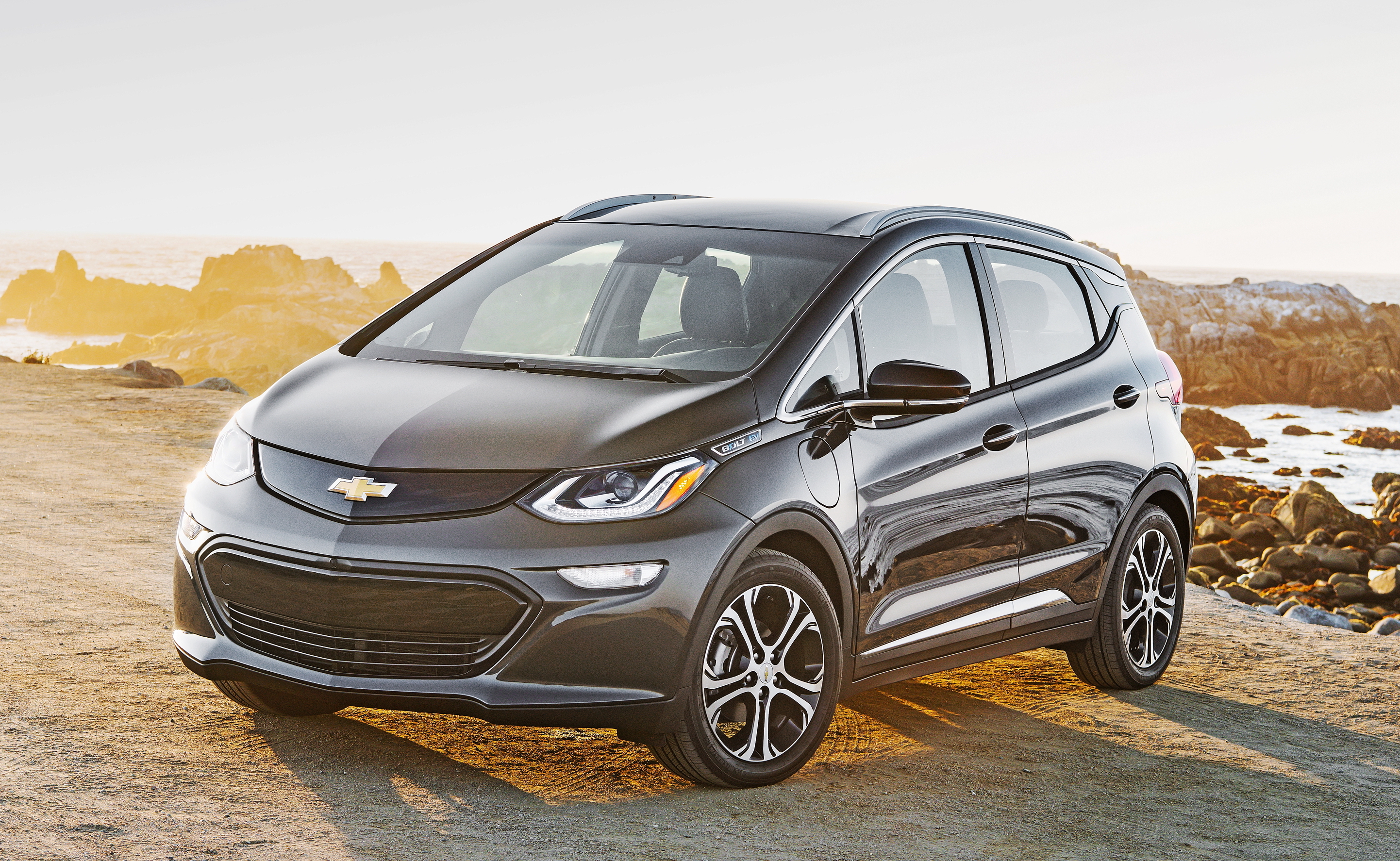 A black 2018 Chevrolet Bolt EV parked on a sunny beach.