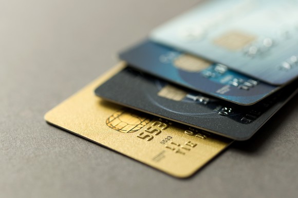 Pile of four credit cards sitting on a flat surface.