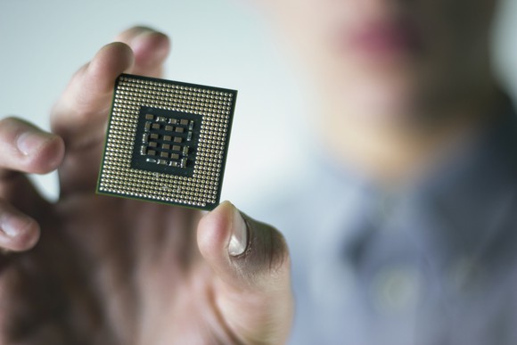 A hand holding what looks like an Intel microprocessor