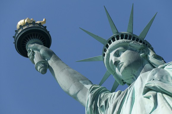 Statue of Liberty looking up from ground, under a blue sky.