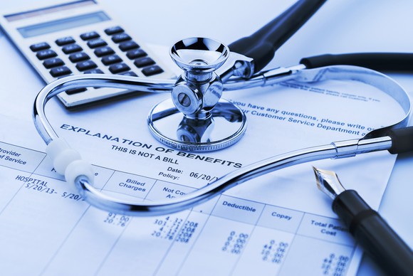 Health insurance benefits form with stethoscope, calculator, and pen on top.
