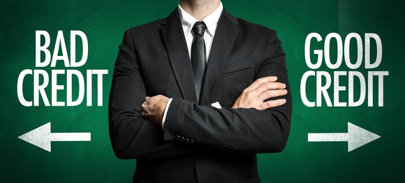 torso of man in suit with arms crossed there are arrows to the right and left of him pointing to bad credit and good credit