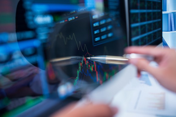 person pointing to a stock chart with a pen.