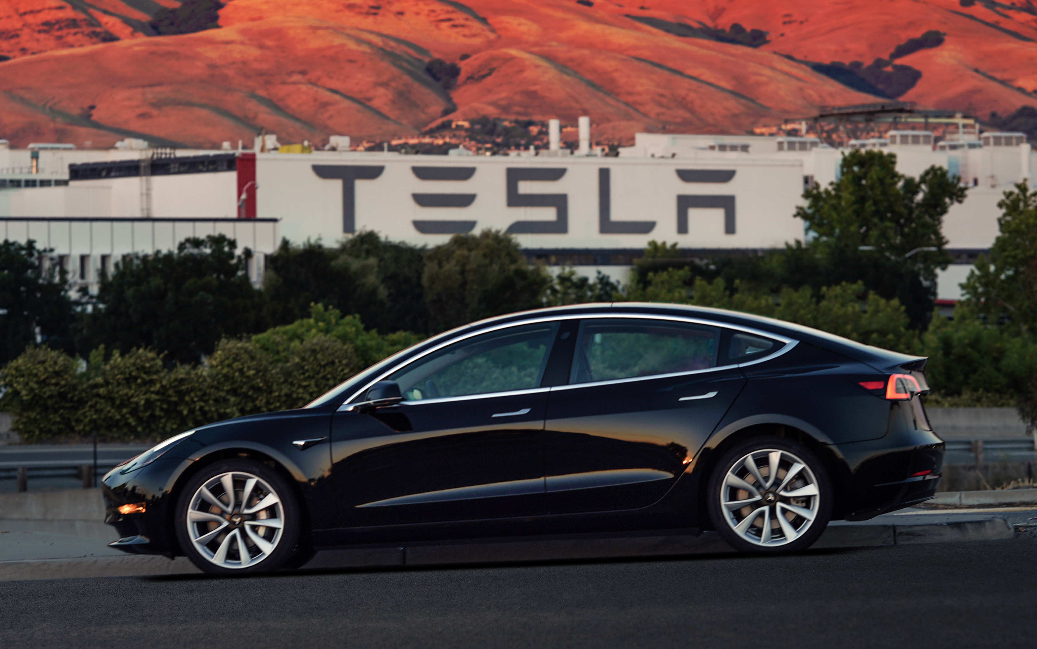 A black Tesla Model 3 sedan in front of the company's factory in Fremont, California. 