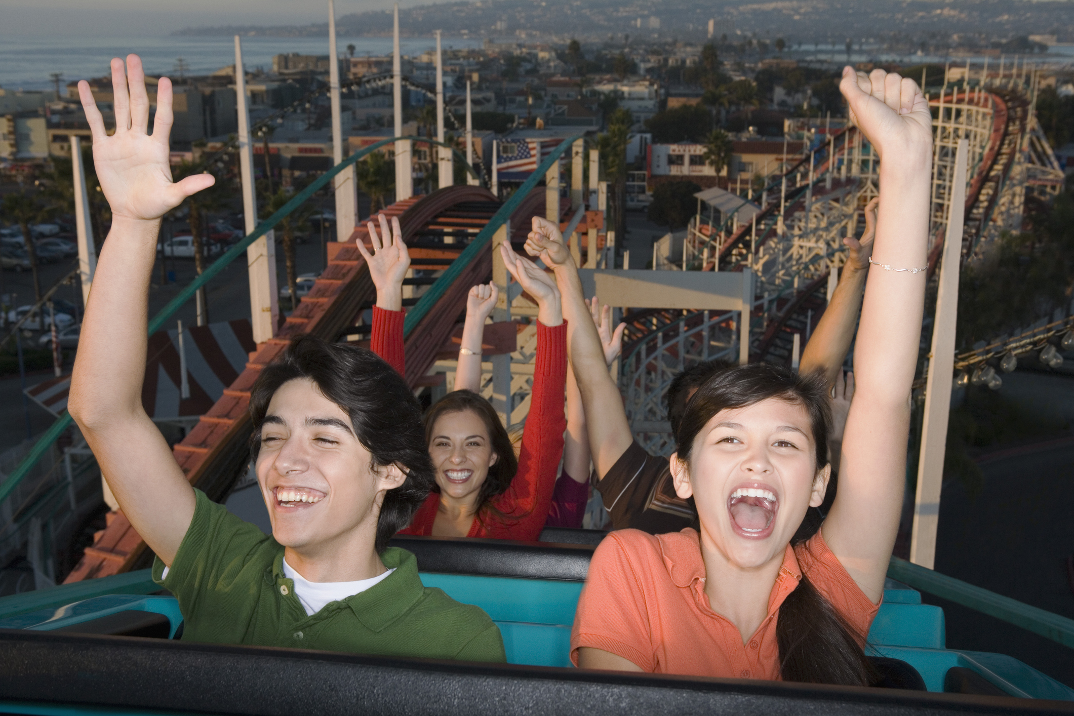People on a roller coaster with their hands up, smiling