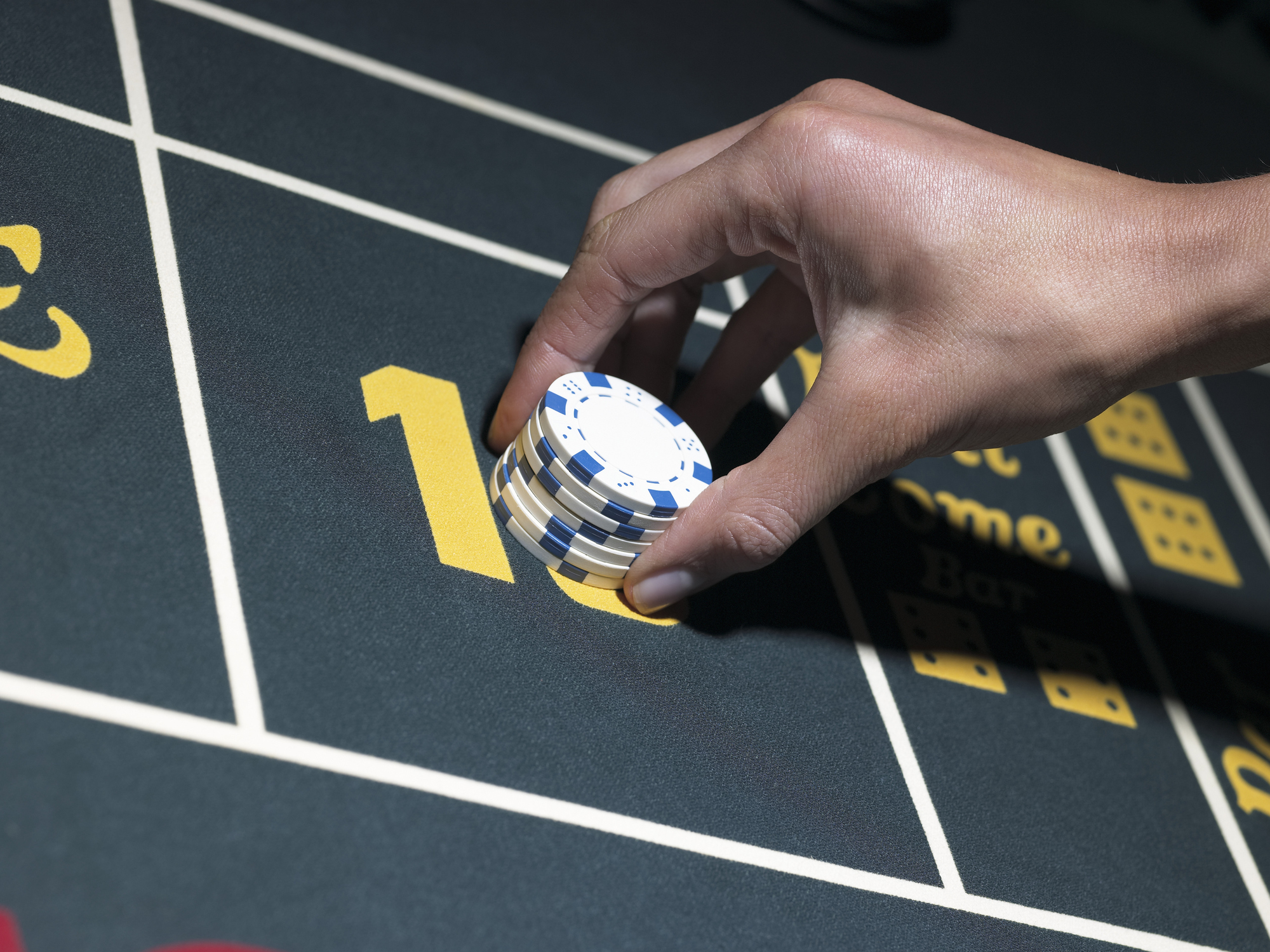 Hand placing gamingchips on a craps table.