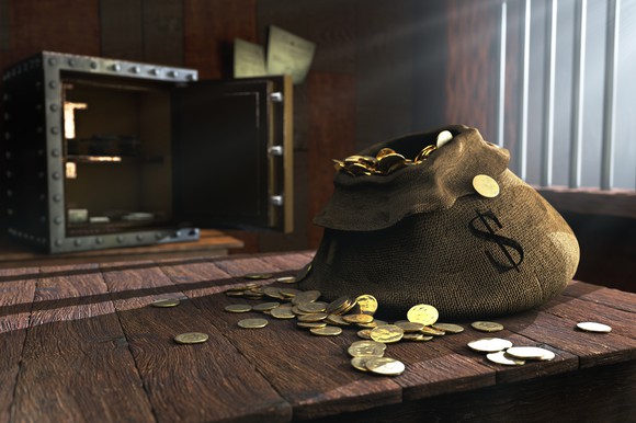 An open safe with a bag full of money on a table.