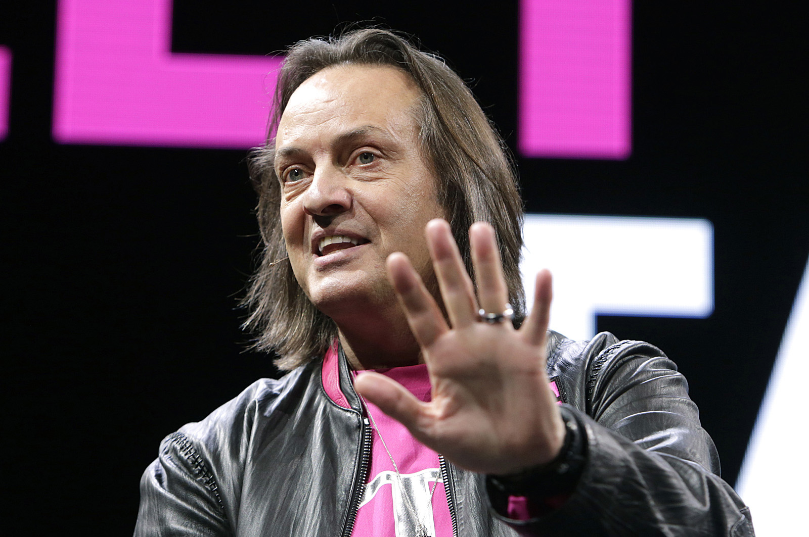 John Legere holding his hand out while speaking on stage