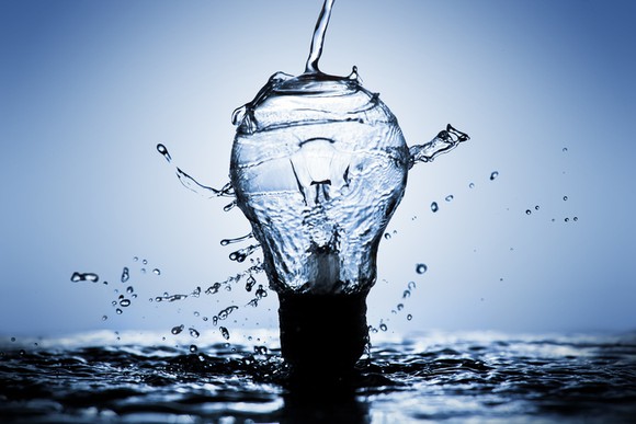 A light bulb made of water bursting over a pool of water.