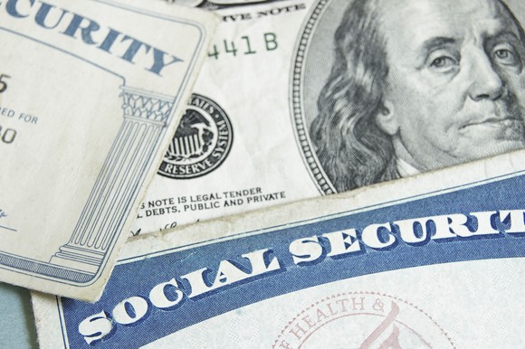 Two Social Security cards sitting on top of a $100 bill.