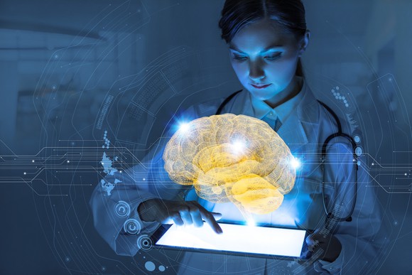 Female doctor holding tablet with digital image of brain displayed over tablet