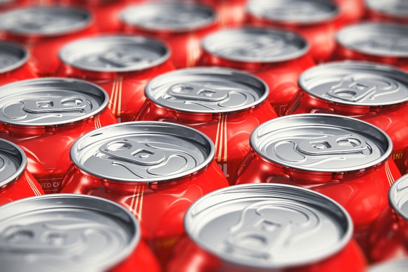Pop cans lined up on a table.