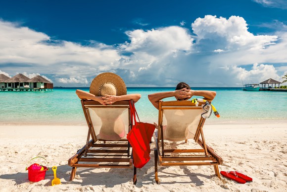man and woman relaxing in lounge chairs on a beach in the Maldives