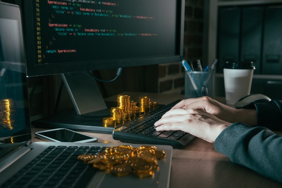 Mined cryptocurrency tokens "appearing" around a computer.
