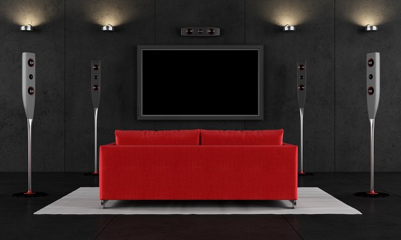 A home theater with a flat-screen TV and a red love seat.