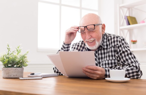 Senior man holding papers and lifting up glasses on his face