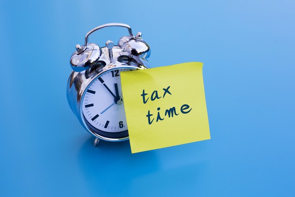Alarm clock with a post-it taped on that says tax time