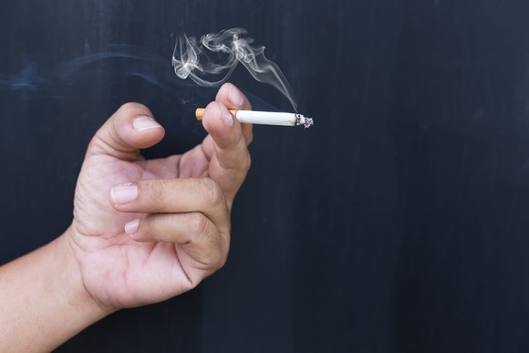 Hand holding a lit cigarette.