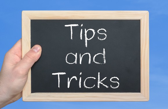 hand holding small blackboard on which is written tips and tricks