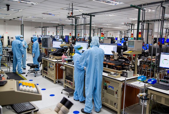 Workers in a factory clean room, wearing surgical-type scrubs.