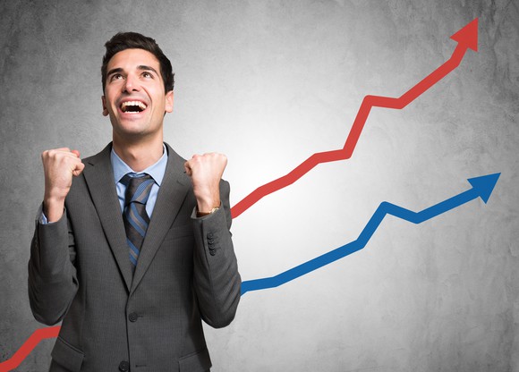 A man cheers as he watches a rising financial chart.