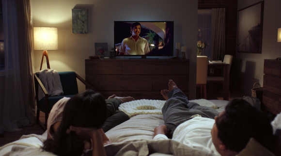 A woman and man watch Netflix from bed