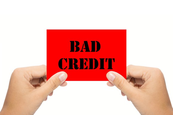 Two hands hold a sign reading bad credit