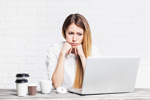 Woman at a laptop, looking sad