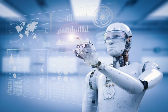 A humanoid robot pointing with its finger to a transparent screen with various images on it.