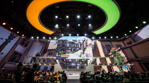 An audience watching players on a stage compete during a regular season match of Overwatch League.