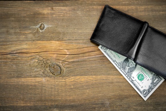 Wallet on a table with a dollar bill coming out.