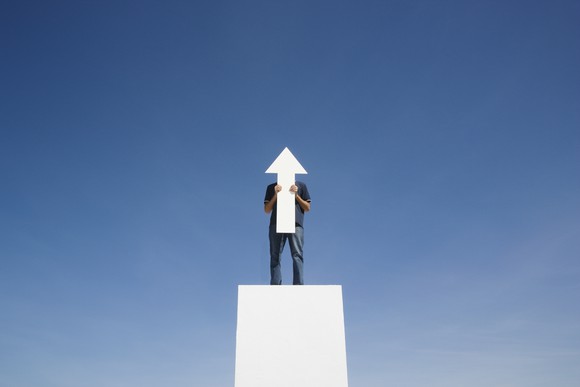 A man holding a white arrow point up.