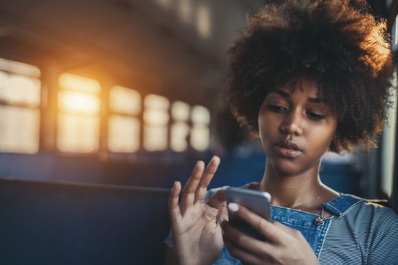 A woman using a smartphone while riding on a bus