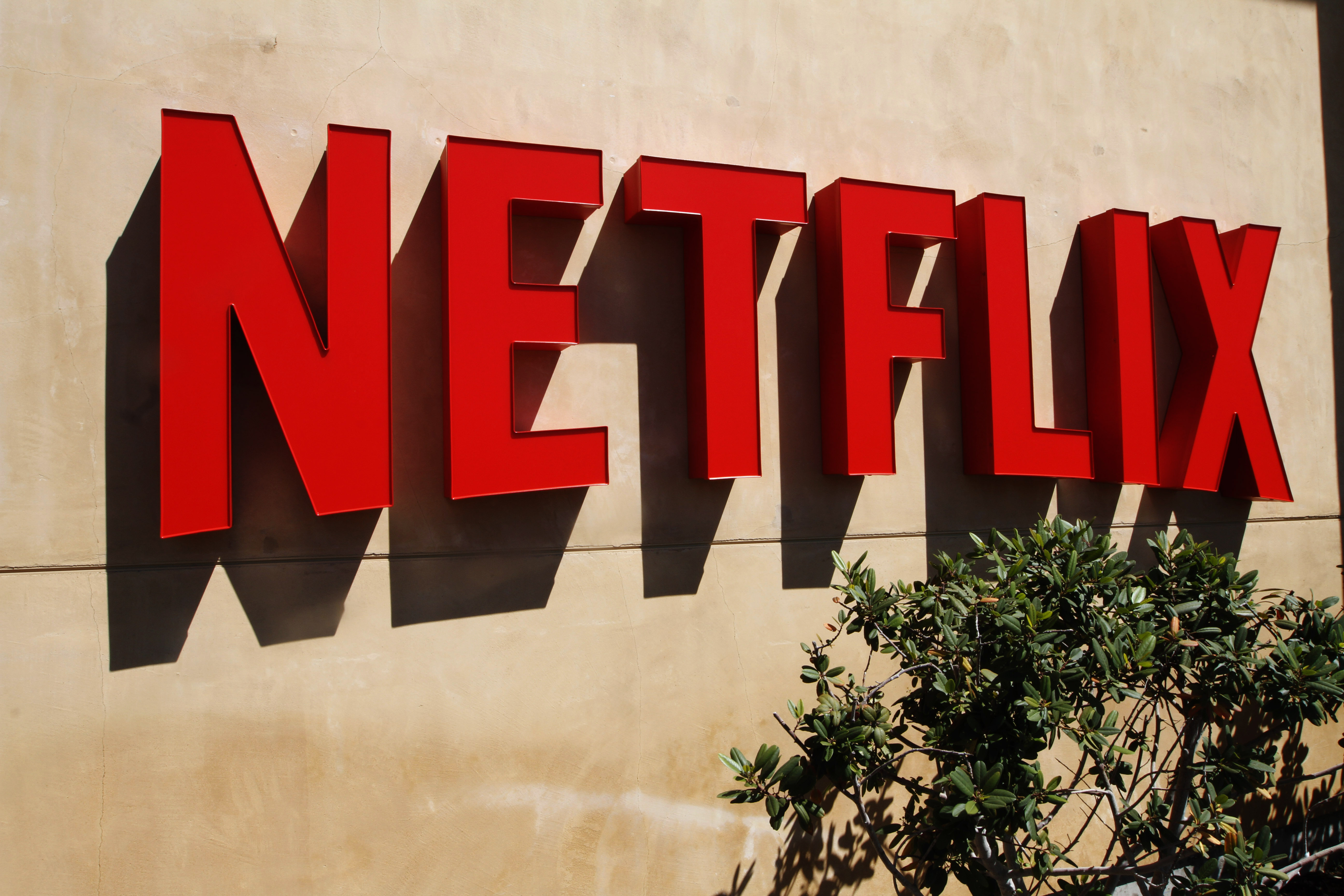 Red Netflix logo on a beige stucco wall outside company headquarters.