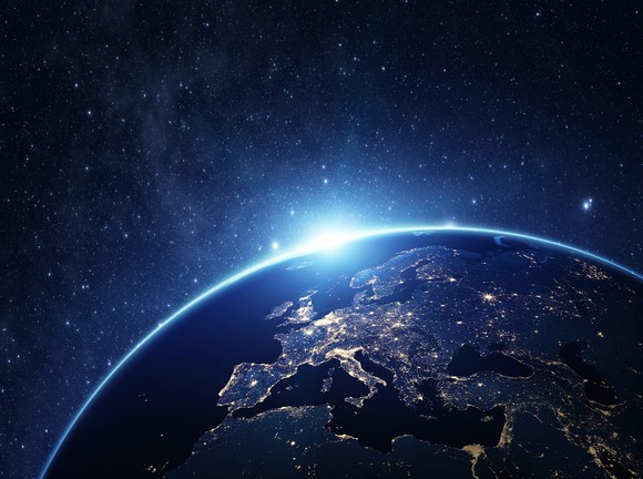 view of continental Europe from space lit up as sun peeks over the rounded edge of the earth
