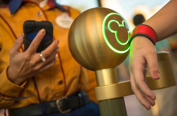 A guest uses a MagicBand to enter a Disney World theme park.