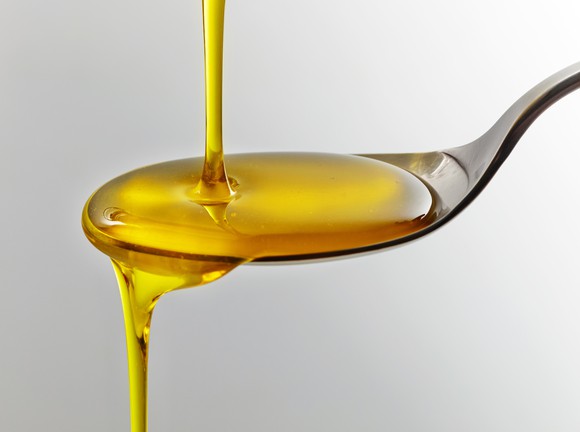 Fish oil being poured over a spoon.