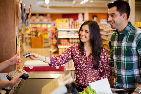 Couple using a credit card to pay for purchases in a grocery store.