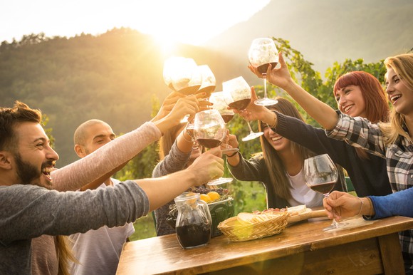 Happy friends having fun and drinking wine in autumn time