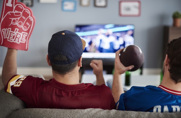 Two men watch football on TV.