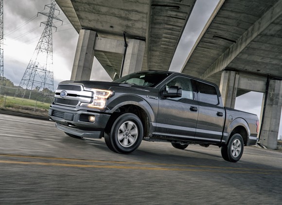 Ford's 2018 F-150 driving under a concrete bridge, with power lines in the background