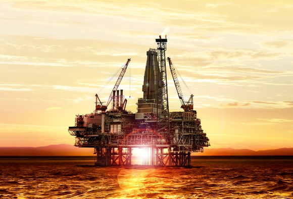 An offshore oil platform with the sun bursting through.