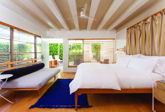 A large white bed in a hotel room surrounded by windows