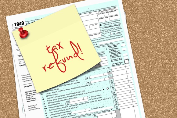 Post it note that says tax refund on top of a tax form