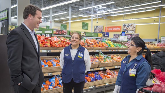 CEO Doug McMillon talks with two Walmart associates in the produce section.