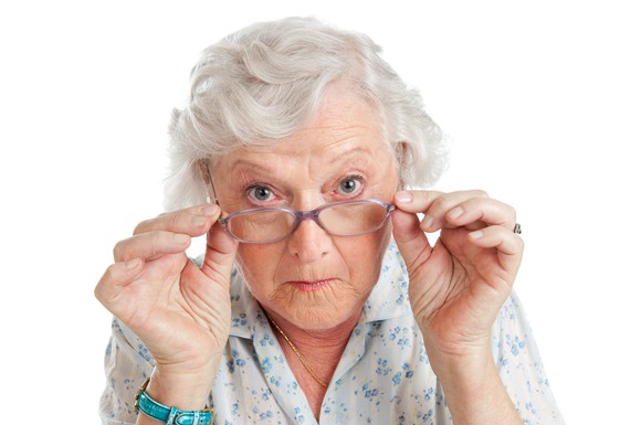 White-haired woman peering with interest over her glasses